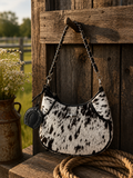 Loyal West Lueve hairon leather bag hanging on wooden post in countryside setting with Loyal West charm