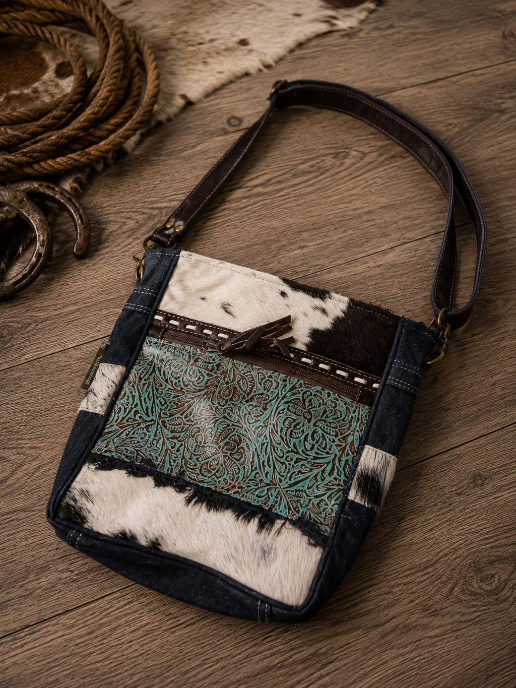 Forest Sky Shoulder Bag - front view showing turquoise tooled leather panel and cowhide on rustic wood
