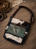 Forest Sky Shoulder Bag - front view showing turquoise tooled leather panel and cowhide on rustic wood