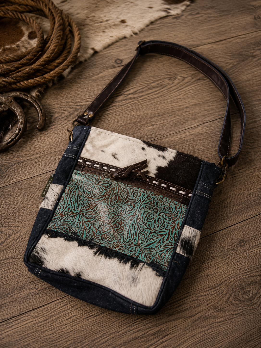 Forest Sky Shoulder Bag - front view showing turquoise tooled leather panel and cowhide on rustic wood